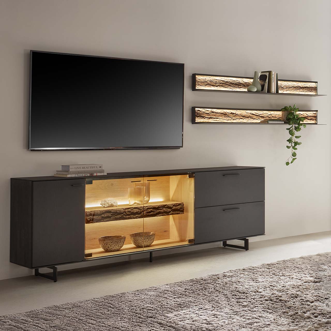 Hartmann RUNA 8410 - Wohnkombination Nr. V54 - vierteilig - Kerneiche Natur Anthrazit gebeizt Modernes Wohnzimmer mit vierteiliger Wohnwand bestehend aus einem Lowboard aus massiver Kerneiche Natur, anthrazit gebeizt mit beleuchtetem Glasausschnitt auf Metallkufen und zwei Wandregale aus Metall mit sichtbarer Baumrinde