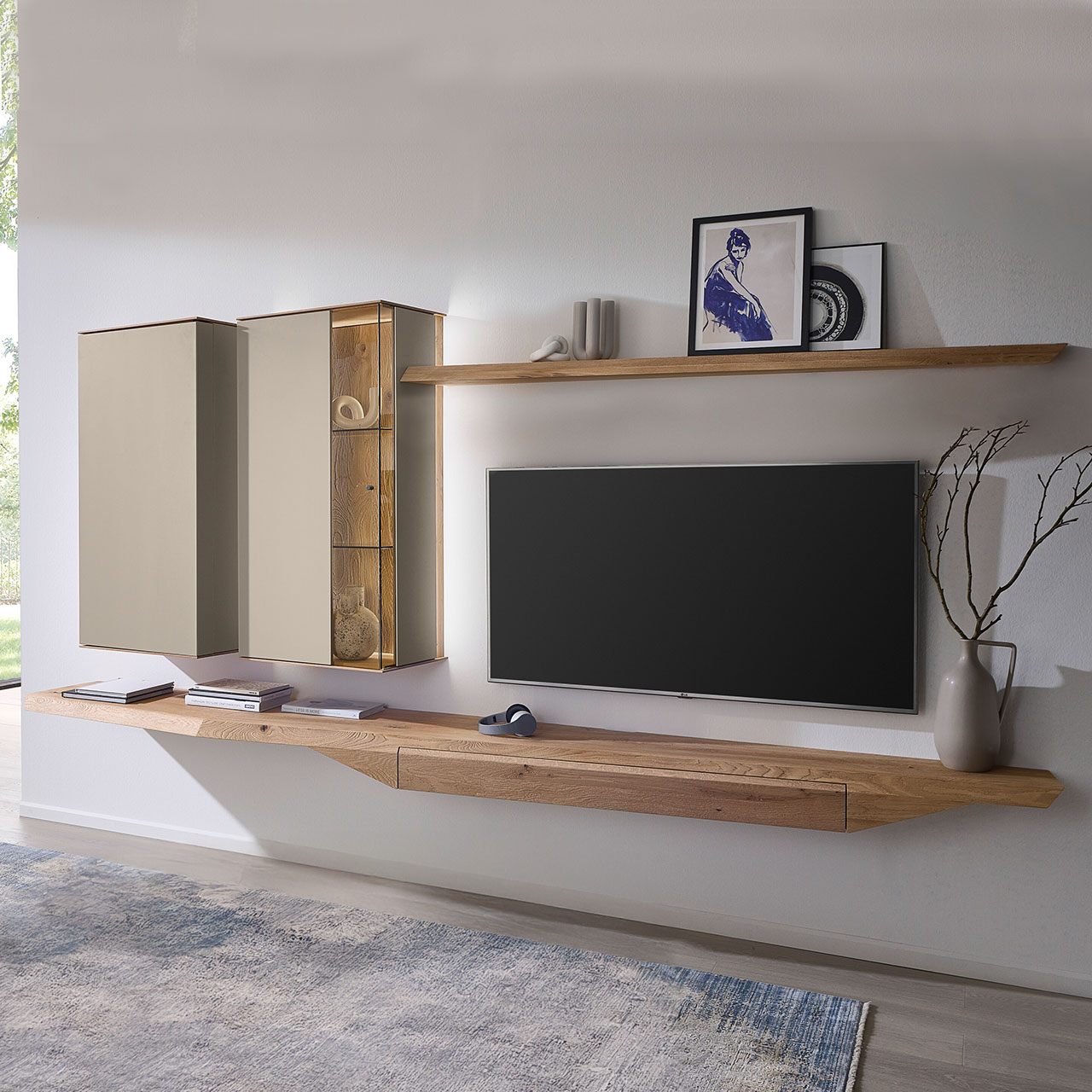 Moderne, vierteilige Wohnwand aus massiver Kerneiche Natur mit Lack Sand und Riffholz im asymmetrischen Design. Bestehend aus Hängelowboard mit Schubkasten, Hängevitrine in Holz/Lack, Hängeschrank in Lack sowie einem Wandboard aus Riffholz.