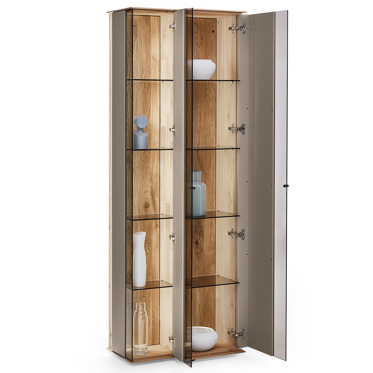 Moderne Standvitrine aus massiver Kerneiche Natur mit Lackfronten in Sand. Mit zwei geöffneten Glastüren in asymmetrischem Design. Dahinter sichtbar Glaseinlegeböden und die beleuchtete Riffholzrückwand.