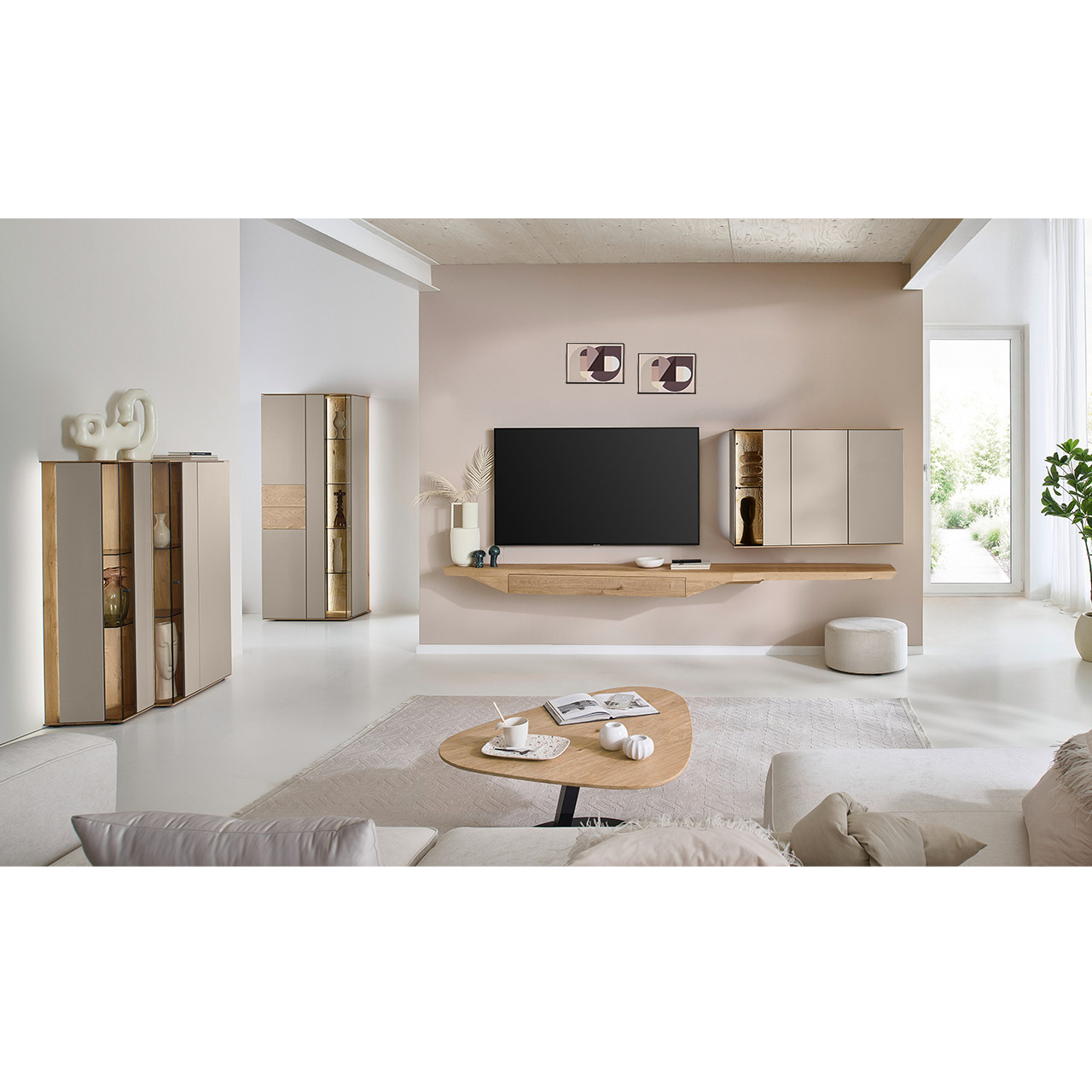 Wohnzimmer mit moderner Massivholzwohnwand kombiniert mit Lack bestehend aus langem Hängelowboard aus Riffholz und Hängevitrine in Lack/Sand - im asymmetrischen Design. Links passendes Highboard mit Glastüren, davor asymmetrischer Beistelltisch.