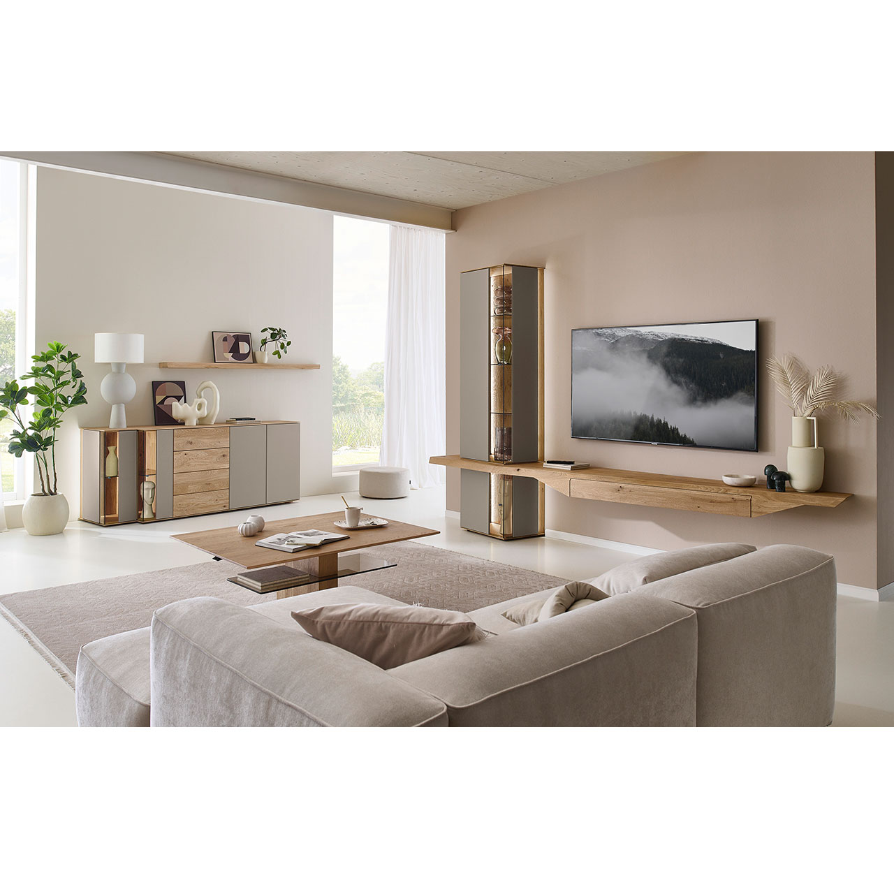 Wohnzimmer mit Massivholzwohnwand aus Kerneiche mit Lack Sand und Riffholz bestehend aus Hängelowboard mit Schubkasten, Hängevitrine sowie Unterbauvitrine - im asymmetrischen Design. Links passendes Sideboard mit Glastüren, davor Holz-Couchtisch.