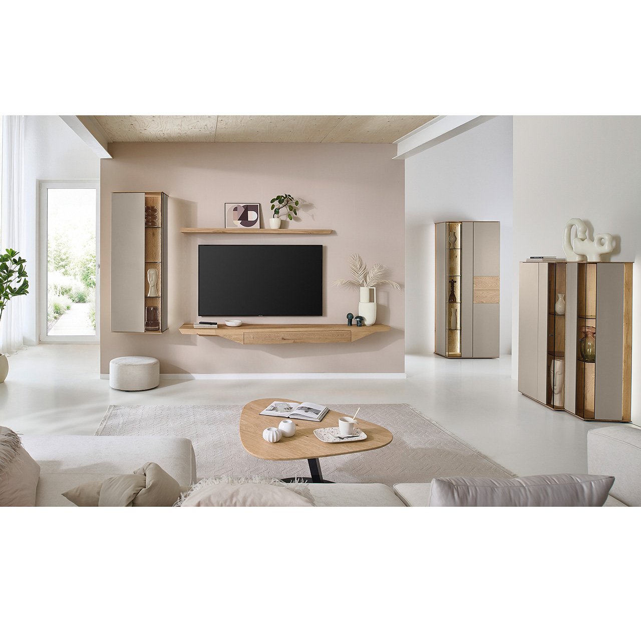 Wohnzimmer mit moderner Massivholzwohnwand bestehend aus Hängelowboard mit Schubkasten, Hängevitrine sowie einem Holzei-Wandboard - im asymmetrischen Design. Rechts passendes Highboard mit Glastüren, davor asymmetrischer Couchtische.