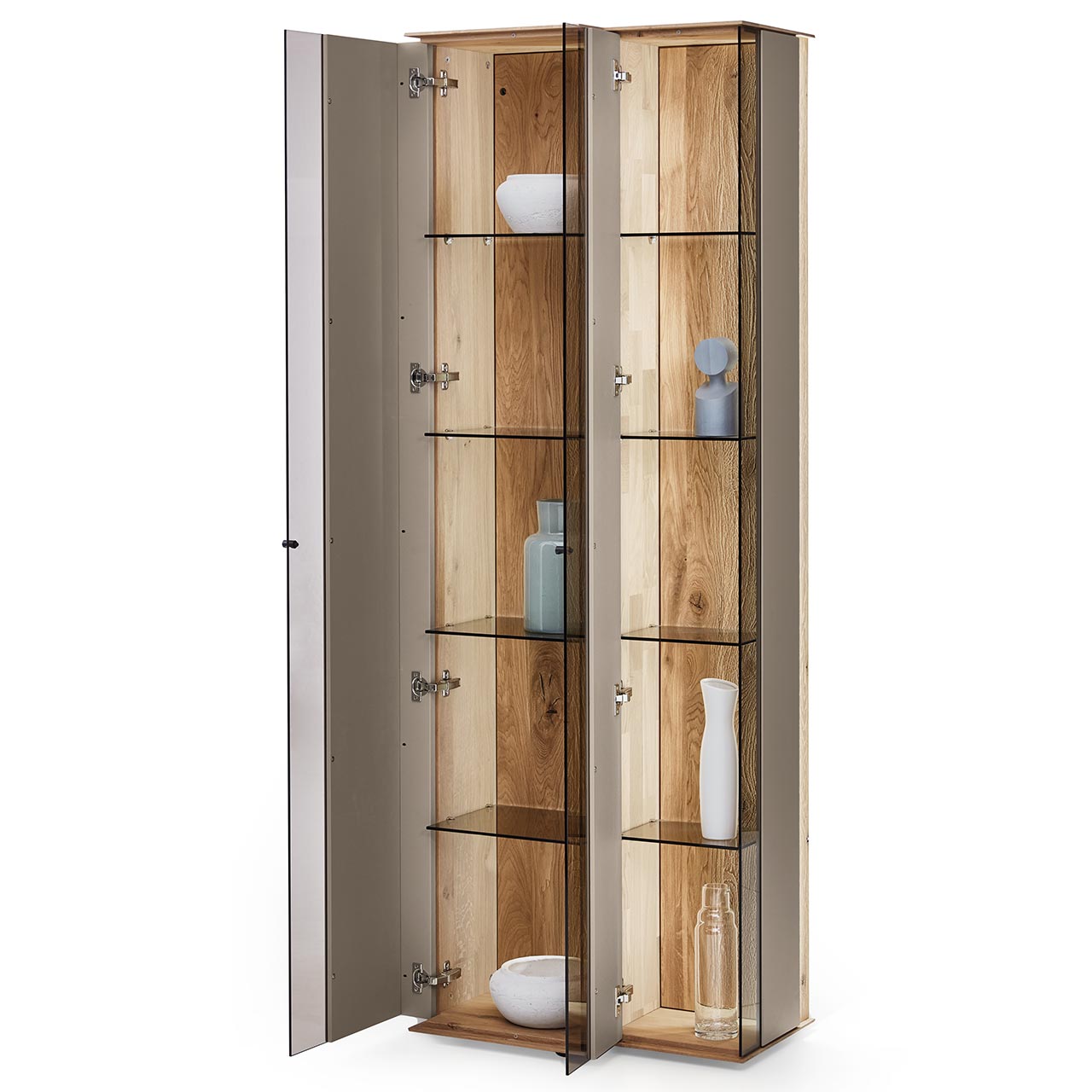 Moderne Standvitrine aus massiver Kerneiche Natur mit Lackfronten in Sand. Mit zwei geöffneten Glastüren in asymmetrischem Design. Dahinter sichtbar Glaseinlegeböden und die beleuchtete Riffholzrückwand.