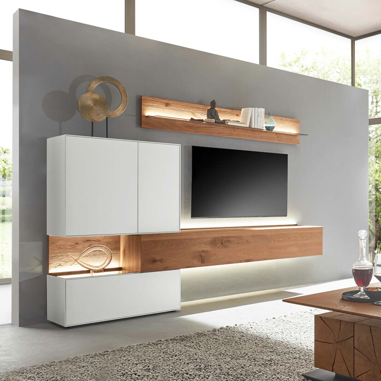 Hartmann TORIDO - Wohnwand 7270 Nr. V20 - fünfteilig - Birke Lack weiß & Kerneiche Umato Moderne Wohnwand aus massiver Birke weiß lackiert mit Kerneiche Umato bestehend aus einem Holz-Hängelowboard seitlich eingefasst in einen weißen Unter,- und Hängeschrank mit beleuchteter Rückwand und einem Holz-Wandpaneel mit Glasablageboden.
