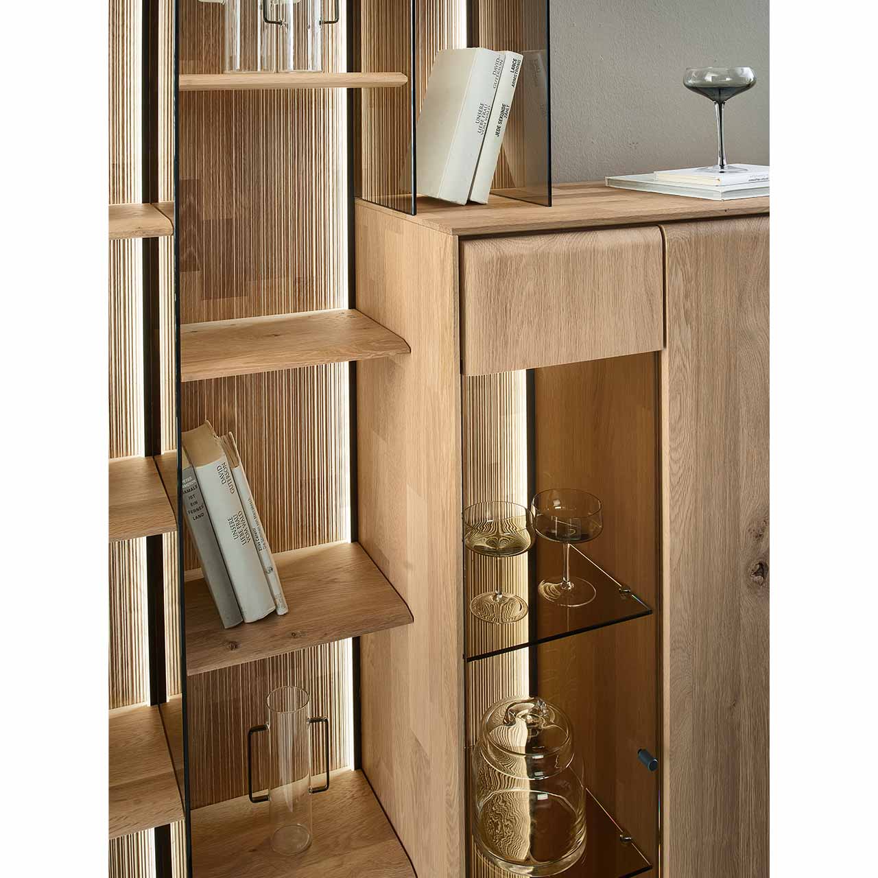 Detailaufnahme eines Wandregals als Anbauelement für Highboards. Das Wandregal mit geschroppter Rückwand, beleuchteten Seitenwänden aus Parsolglas und edlen Holzböden ist integriert in ein passendes VALA Highboard Nr. 7141.