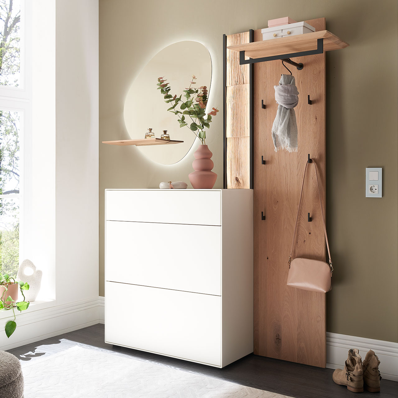 Moderne dreiteilige Garderobe aus Kernbirke und Kerneiche Natur: Wandpaneel aus Holz mit Kleiderstange, Haken und Spaltholz-Akzent, ein Stauraumschrank mit Schubkasten und Klappen in Lack weiß und ein ovaler Spiegel mit Ablage.