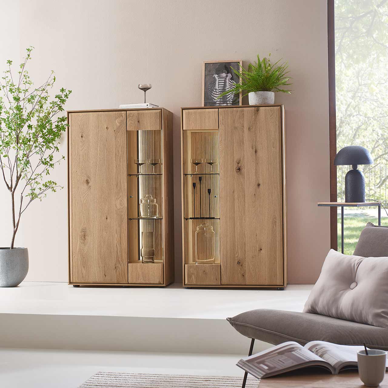 Zwei moderne Highboards aus massivem Eichenholz mit je zwei geschlossen Holz - und Glas/Holztüren - im modern eingerichtetem Wohnzimmer an der Wand stehend.