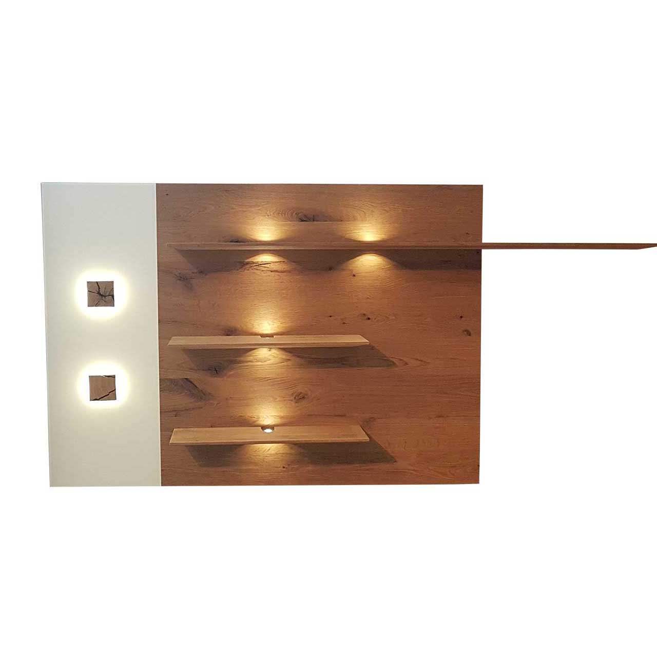 Modernes Wandpaneel aus massiver Kerneiche Umato mit drei, beleuchteten Ablageböden, links mit Mattglas weißer Applikation und zwei kleinen, rechteckigen Hirnholzscheiben.