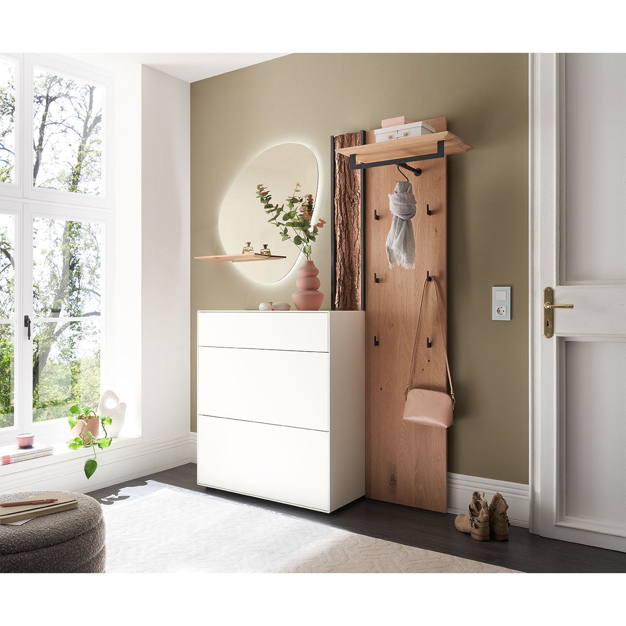 Flur mit modernen Garderobenmöbeln aus Kernbirke und Kerneiche Natur: Wandpaneel aus Holz mit Kleiderstange, Haken und Rinden-Akzent. Ein Stauraumschrank mit Schubkasten und Klappen in Lack weiß, ein ovaler Spiegel mit Ablage.