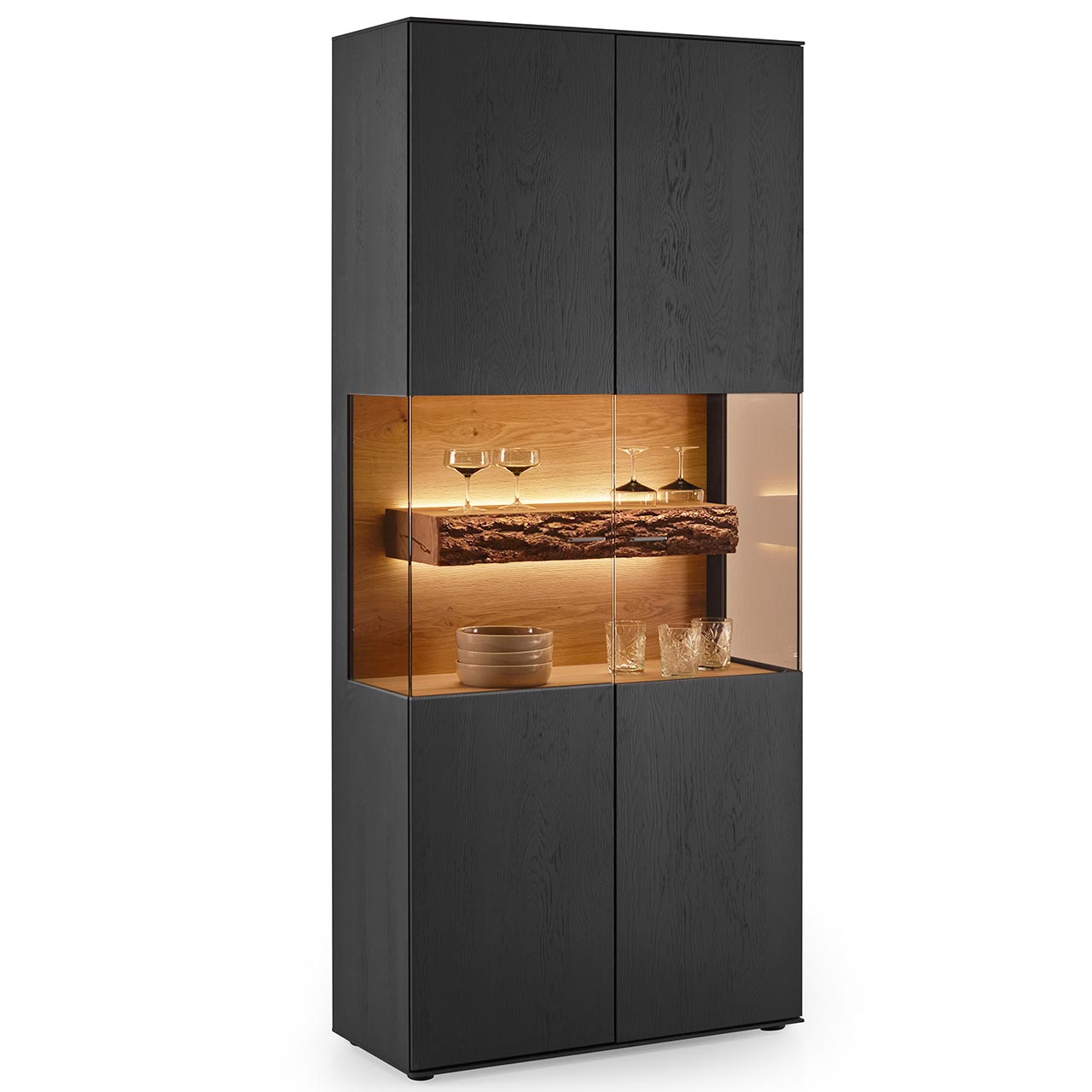 Hartmann RUNA - Standvitrine 8410-0091 - Kerneiche Natur Anthrazit gebeizt Moderne Standvitrine aus massiver Kerneiche Natur in Anthrazit gebeizt mit zwei Türen. Mittig ein beleuchteter Glasausschnitt mit sichtbarem Rindenboden.