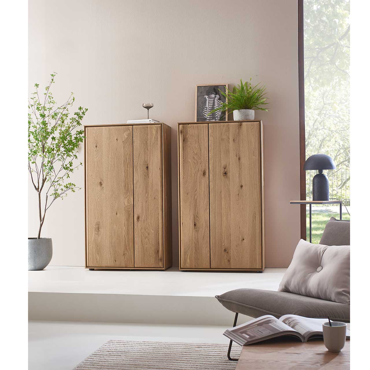 Zwei schlichte Highboards aus massivem Eichenholz mit je zwei geschlossen Holztüren - im modern eingerichtetem Wohnzimmer an der Wand stehend.
