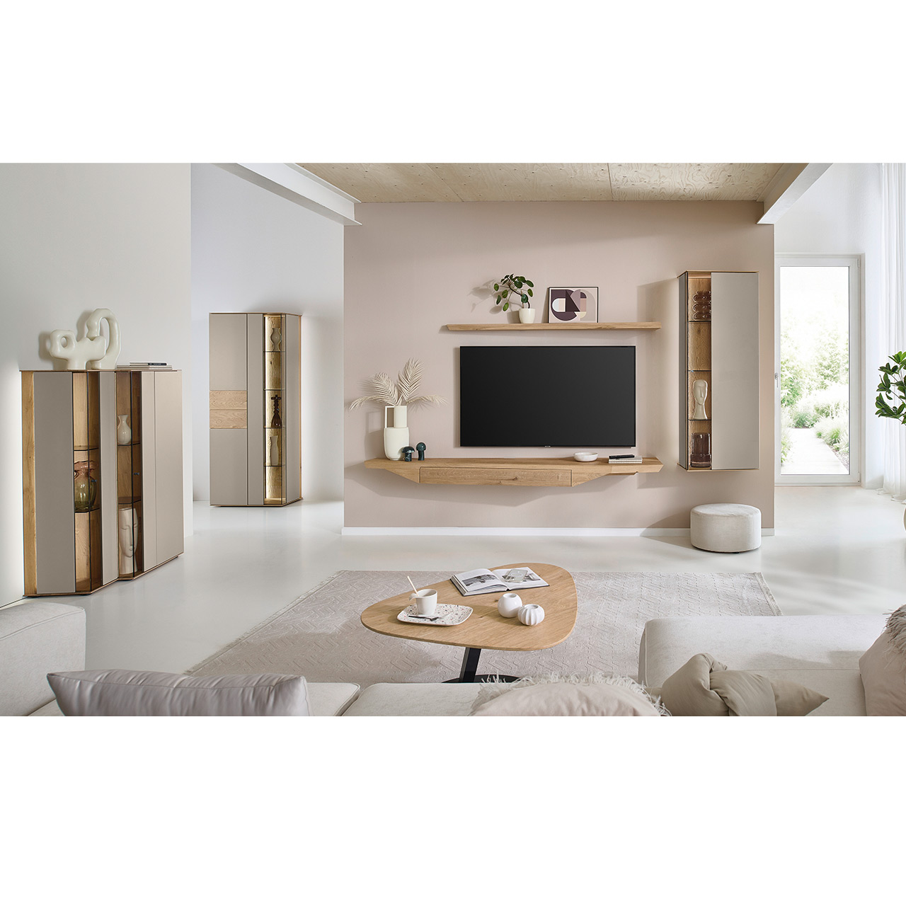 Wohnzimmer mit moderner Massivholzwohnwand bestehend aus Hängelowboard mit Schubkasten, Hängevitrine sowie einem Holzei-Wandboard - im asymmetrischen Design. Links passendes Highboard mit Glastüren, davor asymmetrischer Couchtische.