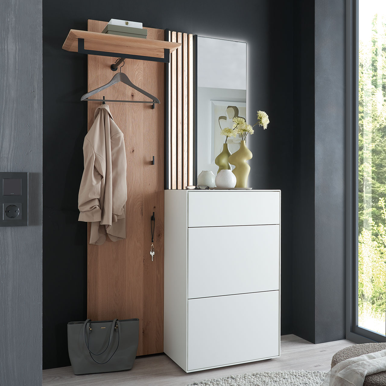 Moderne dreiteilige Garderobe aus Kernbirke und Kerneiche Natur: Wandpaneel aus Holz mit Kleiderstange, Haken und Lamellen-Akzent, ein Stauraumschrank mit Schubkasten und Klappen in Lack weiß und ein rechteckiger Spiegel.