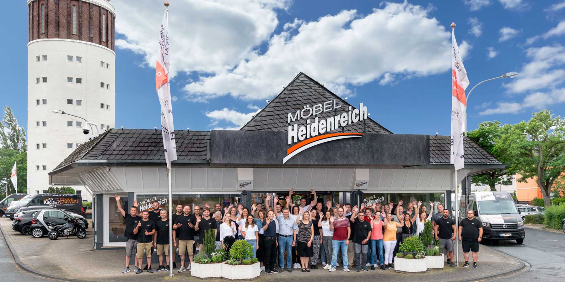 Gruppenfoto der Mitarbeiter vor dem Möbelhaus Heidenreich in Groß-Gerau. Im Hintergrund links steht der bekannte Wasserturm.