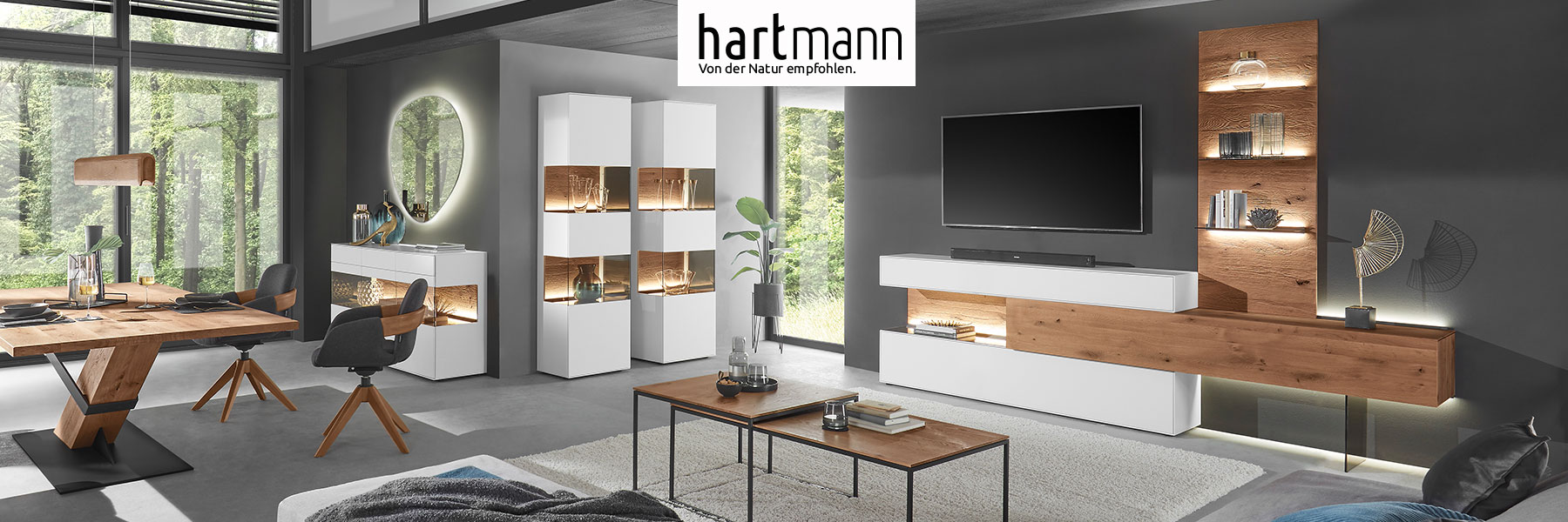 Hartmann Möbel - Möbelserie TORIDO - Birke Lack weiß Hartmann TORIDO - Moderne Möbel aus massiver Birke weiß lackiert kombiniert mit Kerneiche Umato. Ambientebild zeigt Wohn - und Essbereich mit Wohnwand, Couchtisch, Standvitrinen, Sideboard sowie passendem Esstisch mit Stühlen.