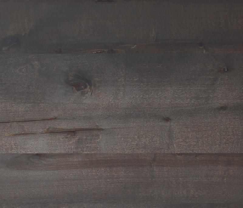 Hartmann Möbel - Holz-Kachel Kernbirke anthrazit gebeizt Holz-Kachel in Kernbirke anthrazit gebeizt mit lebendiger Maserung – sichtbare Holzstruktur mit feinen Rissen, Oberfläche in dunklem Graubraunton.