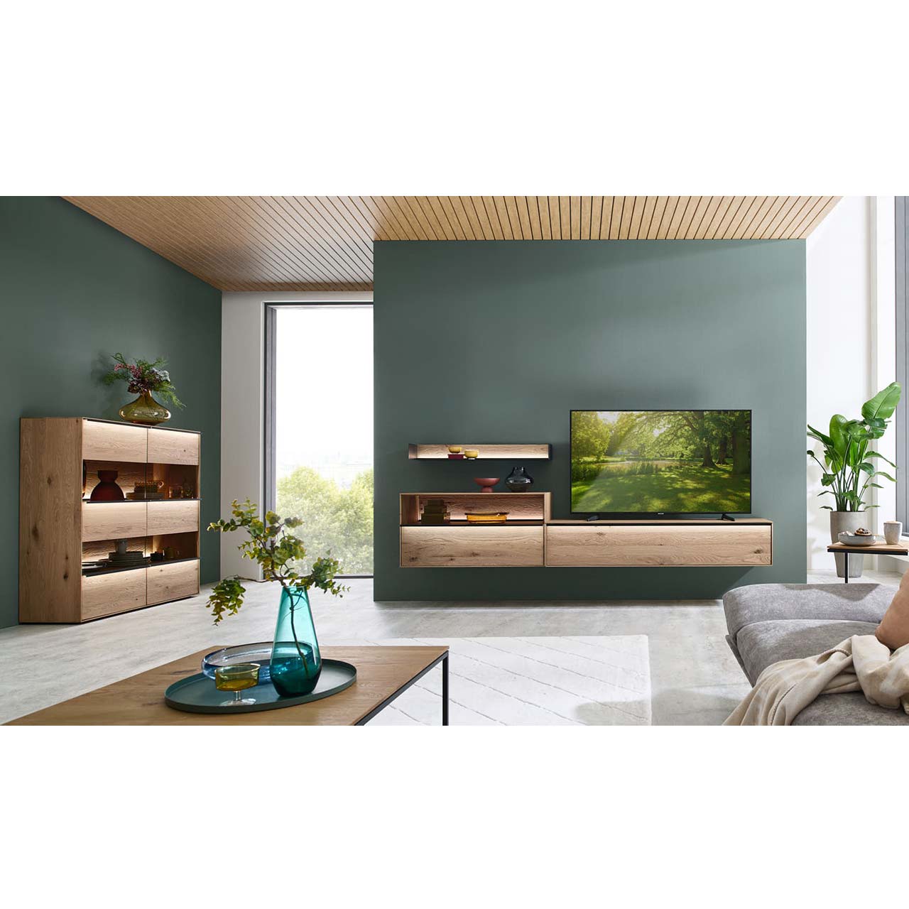 Wohnzimmer mit dunkelgrünen Wänden und natürlichen Massivholzmöbeln