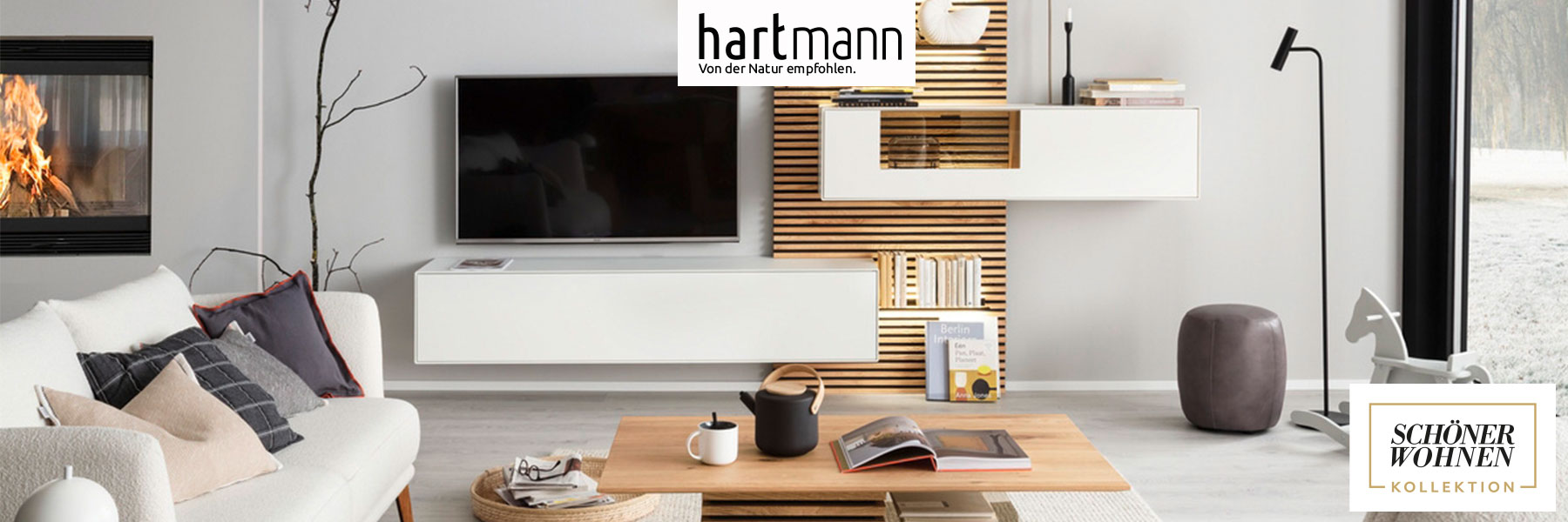 Hartmann YONNA - Wohn und Garderobenmöbel aus Birke weiß lackiert kombiniert mit Kerneiche Natur und Holzlamellen. Ambientebild zeigt ein weißes Hängelowboard und weiße Hängevitrine eingefasst in ein Holz-Lamellenpaneel mit beleuchteten Glasböden.