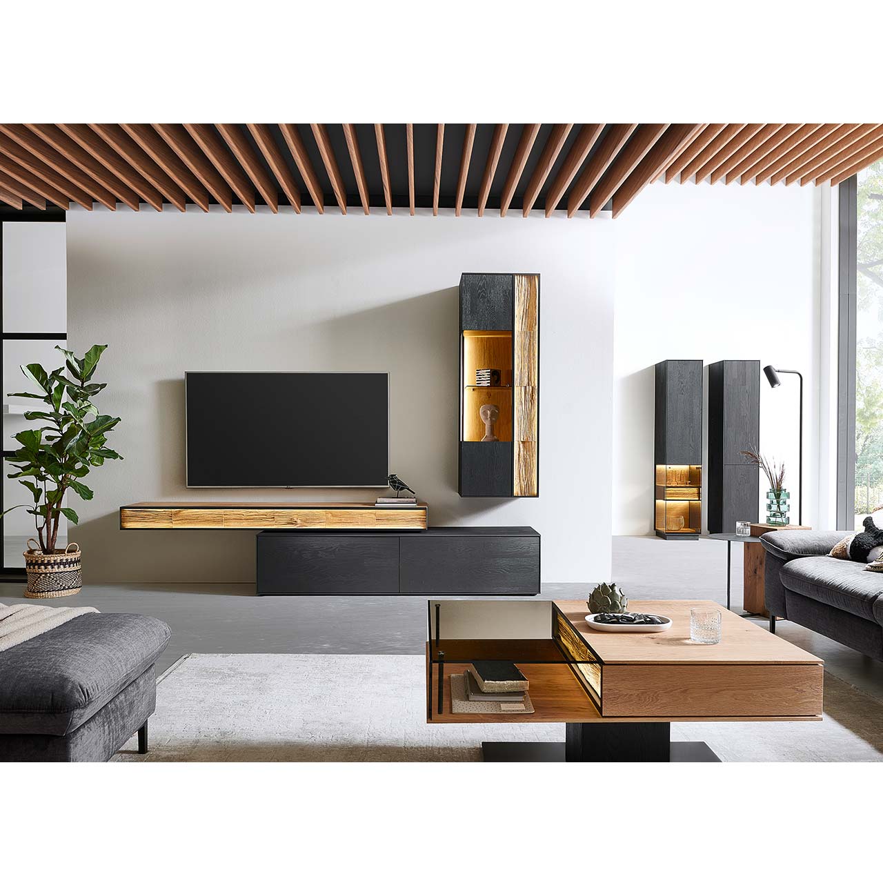 Moderne Wohnwand mit Materialmix aus Lack anthrazit mit Spaltholz-Akzenten und Parsolglas-Vitrinenausschnitten