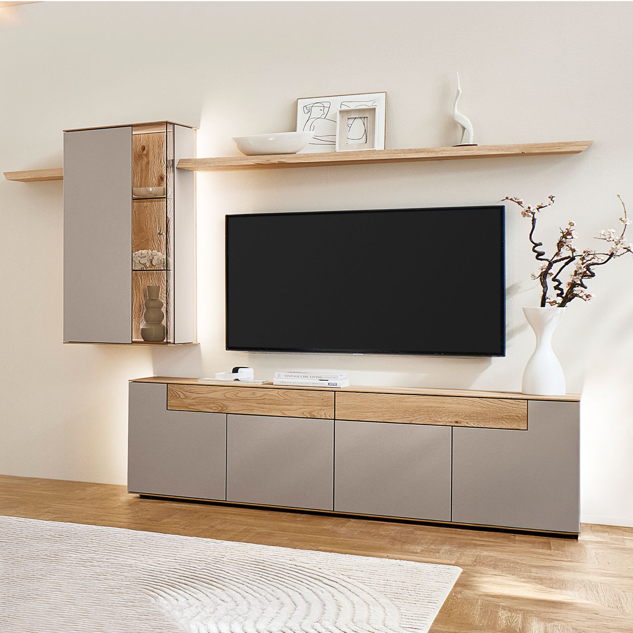 Moderne vierteilige Wohnwand aus massiver Kerneiche Natur mit Lack Sand und Riffholz, bestehend aus einem Lowboard mit Schubkästen, einer Hängevitrine sowie zwei Wandboarden mit Holzboden - im asymmetrischen Design.