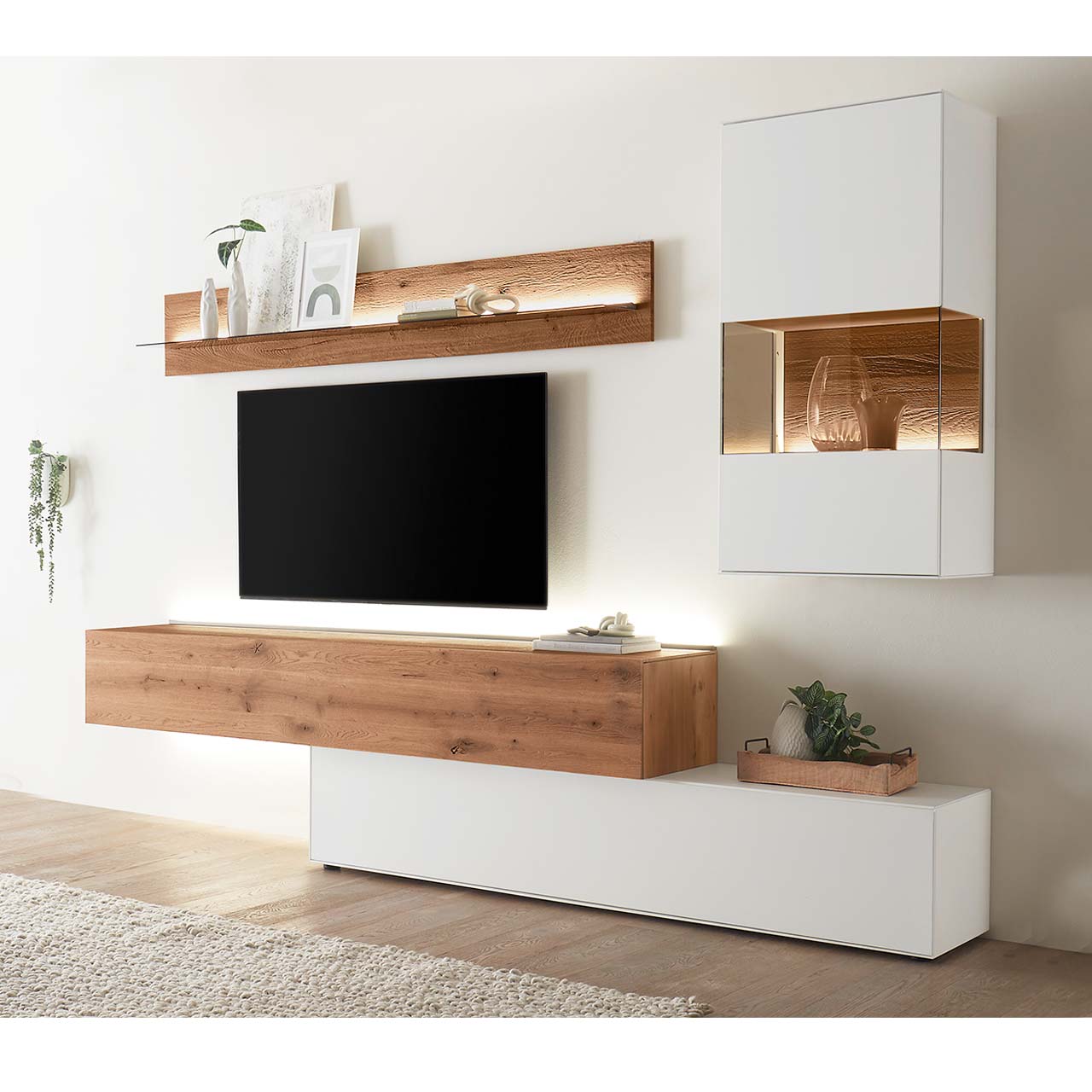 Hartmann TORIDO - Wohnwand 7270 Nr. V24 - vierteilig - Birke Lack weiß & Kerneiche Umato Moderne Wohnwand aus weiß lackierter Birke und dunkler Kerneiche Umato bestehend aus einem Hängelowboard seitlich eingefasst in einen weißen, langen Unterschrank, daneben eine weiße Hängevitrine neben einem Wandregal mit Glasablageboden.