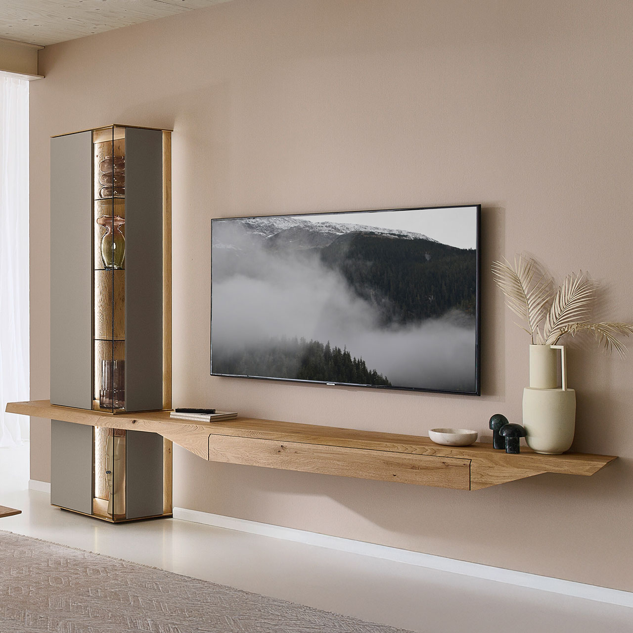 Moderne dreiteilige Wohnwand aus massiver Kerneiche Natur mit Lack Sand und Riffholz im asymmetrischen Design. Bestehend aus einem Höngelowboard mit Schubkasten, einer Hängevitrine sowie einer Unterbauvitrine als Verbindungselement.