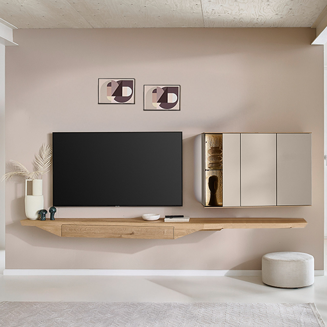 Moderne, zweiteilige Wohnwand aus massiver Kerneiche Natur mit Lack Sand und Riffholz im asymmetrischen Design. Bestehend aus Hängelowboard mit langer Ablagefläche und praktischem Schubkasten und einer Hängevitrine in Holz/Lack mit zwei Türen.