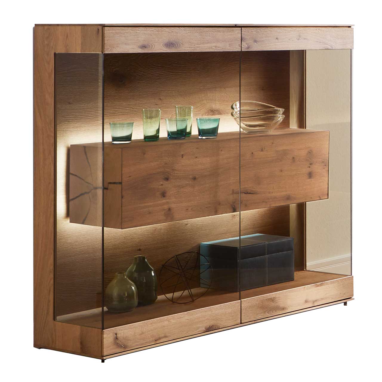 Edles Highboard aus massiver Kerneiche Umato mit großen über Ecke verlaufenden Glastüren in Parsolbronze. Innenliegend ein großer, beleuchteter Hirnholzblock mit Doppelschubkasten.