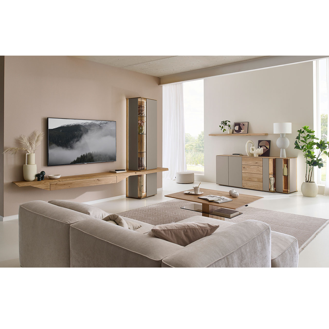 Wohnzimmer mit Massivholzwohnwand aus Kerneiche mit Lack Sand und Riffholz bestehend aus Hängelowboard mit Schubkasten, Hängevitrine sowie Unterbauvitrine - im asymmetrischen Design. Rechts passendes Sideboard mit Glastüren, davor Holz-Couchtisch.