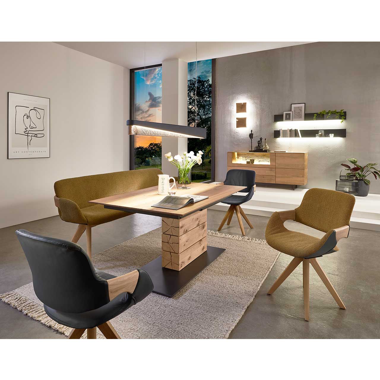 Modernes Esszimmer mit massivem, rechteckigem Holztisch, umgeben von drei Stühlen auf Holzgestell und passender Sitzbank in Senffarbe. Über dem Tisch hängt eine Holz-Balkenleuchte. Rechts an der Wand das passende Sideboard und zwei Metallregale.