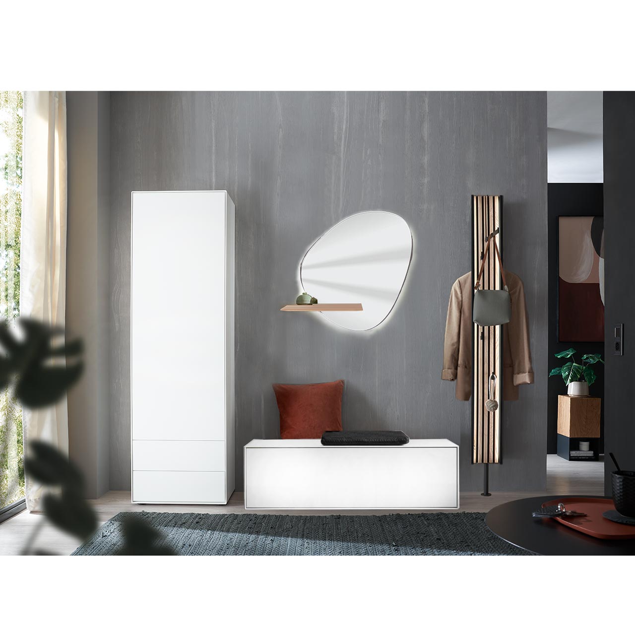 Flur mit modernen Garderobenmöbeln aus massiver Kernbirke in Lack weiß: Ein Hochschrank, ein Garderobenpaneel mit Kleiderstange, Ablageböden und Lamellen-Akzent, eine Sitzbank mit Klappe und ein asymmetrischer Wandspiegel mit Ablage.