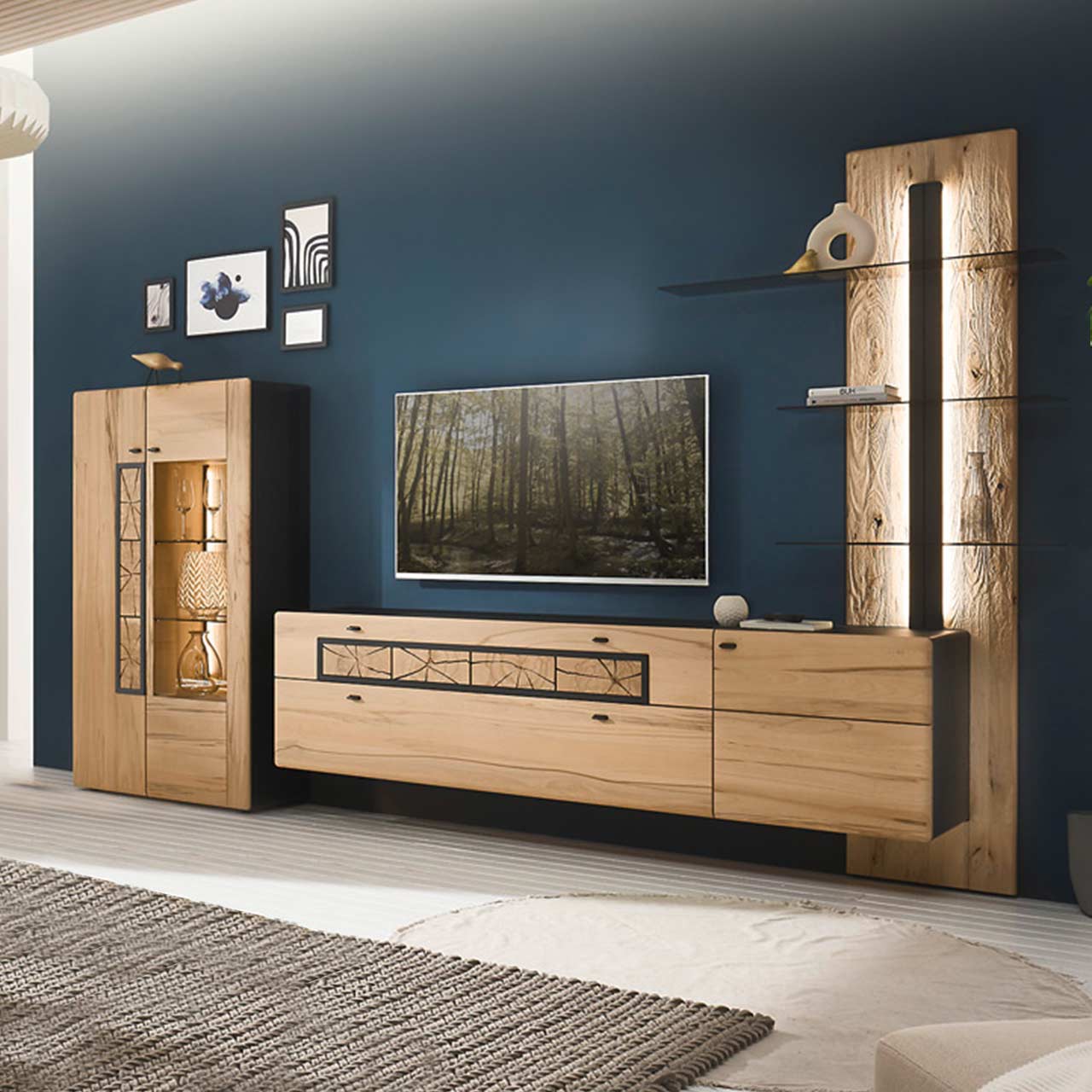 Modernes Wohnzimmer mit dreiteiliger Massivholzwohnwand aus heller Kernbuche vor dunkelblauer Wand: Highboard mit Glasfront, Hängelowboard mit Schubkästen, Wandpaneel mit anthrazitfarbener vertikaler Profilleiste und drei Glasböden.