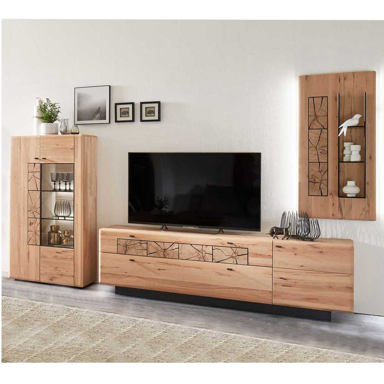 Hartmann KVIK 5560 Wohnwand Nr. 22 - 4teilig Wohnzimmer mit Wohnwand aus massiver Kernbuche. Links ein Highboard mit zwei Türen, eine Holz eine Glastür. Rechts daneben ein Lowboard mit dunklem Sockel. Weiter rechts an der Wand ein hängendes Paneel mit Hirnholzscheiben und drei Glasböden.