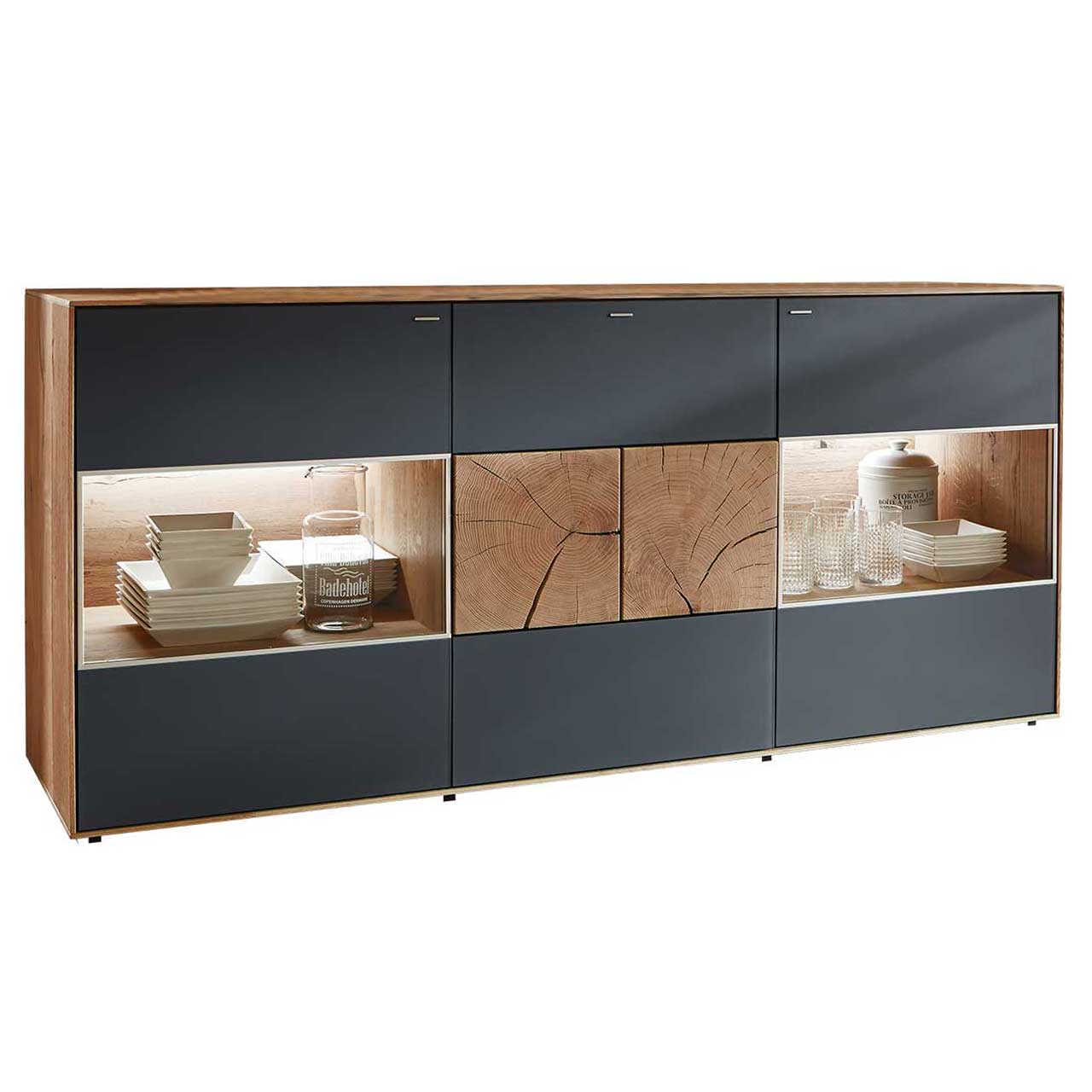 Hartmann CAYA - Sideboard mit Glastüren 7170-4174A Modernes Sideboard aus massiver Kerneiche Umato mit anthrazitfarbenen Mattglasfronten. Rechts und links mit beleuchtetem Glasausschnitt, mittig mit zwei dekorativen, rechteckigen Hirnholzscheiben.