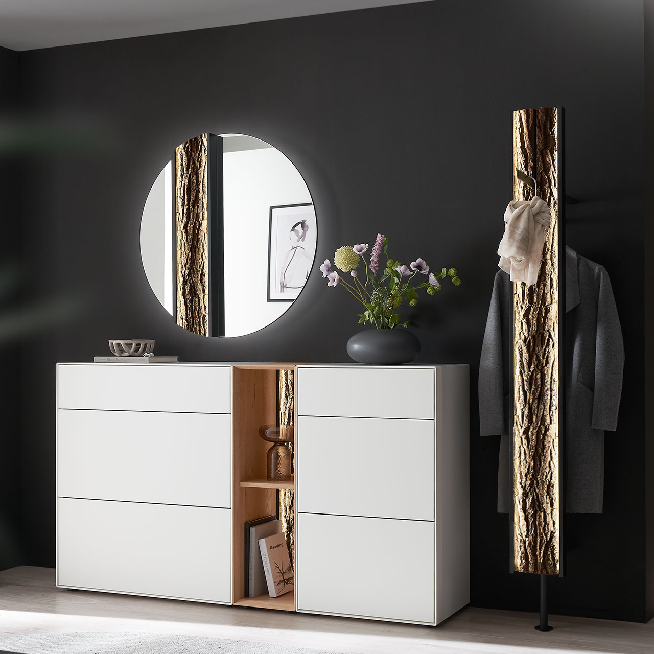 Moderne fünfteilige Garderobe aus massiver Kernbirke und Kerneiche Natur: Regalelement mit Rinden-Rückwand zwischen zwei weiß lackierten Stauraumschränken, dazu ein Garderobenpaneel und ein runder Spiegel mit Rinden-Akzent.
